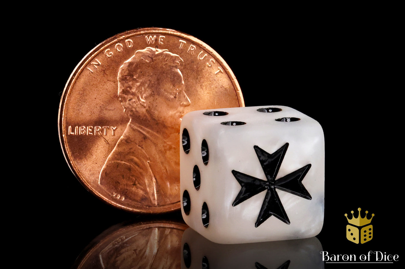 White die with black star design next to a penny on a reflective surface